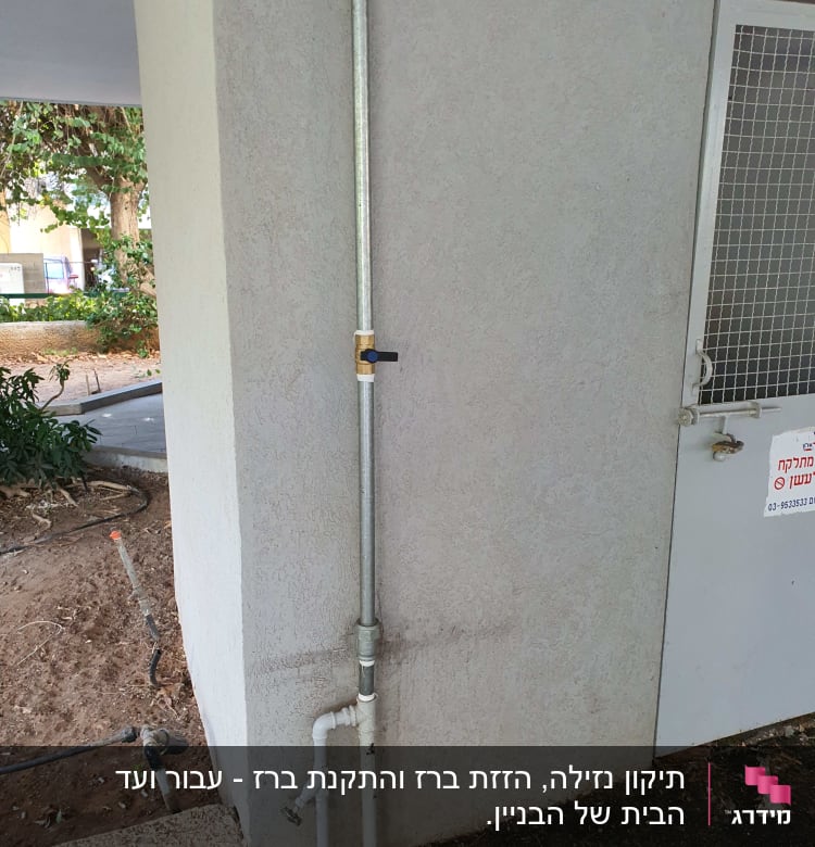 צינור מתכת עם ברז על קיר חיצוני
